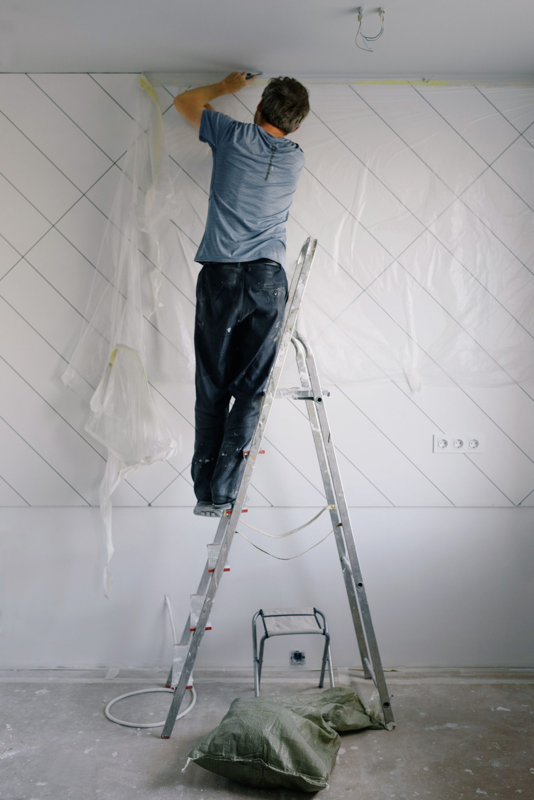 An image of a man putting a plastic cover to protect walls